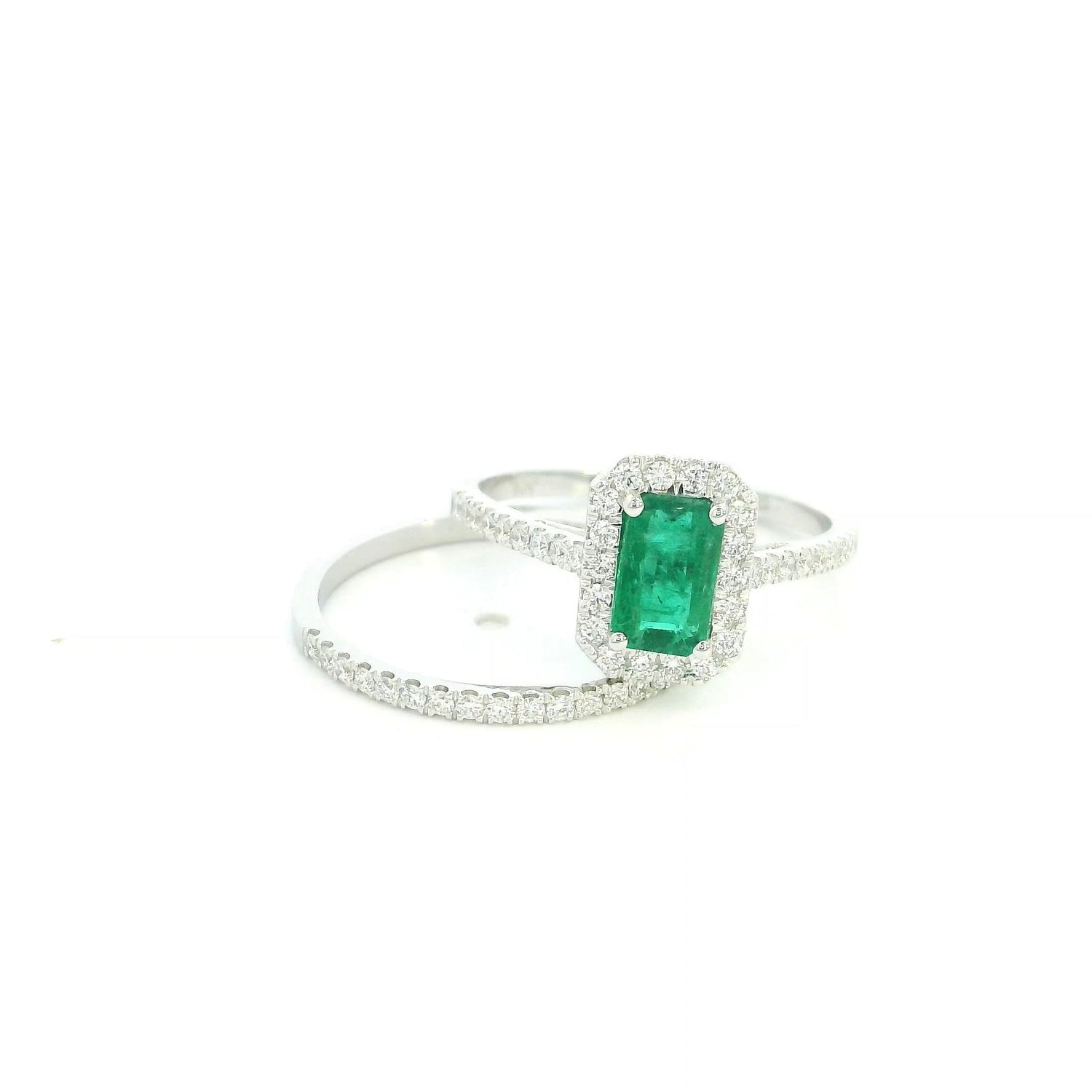 18K white gold emerald bridal set featuring a 0.71 carat natural emerald-cut emerald with a diamond halo and matching diamond wedding band.