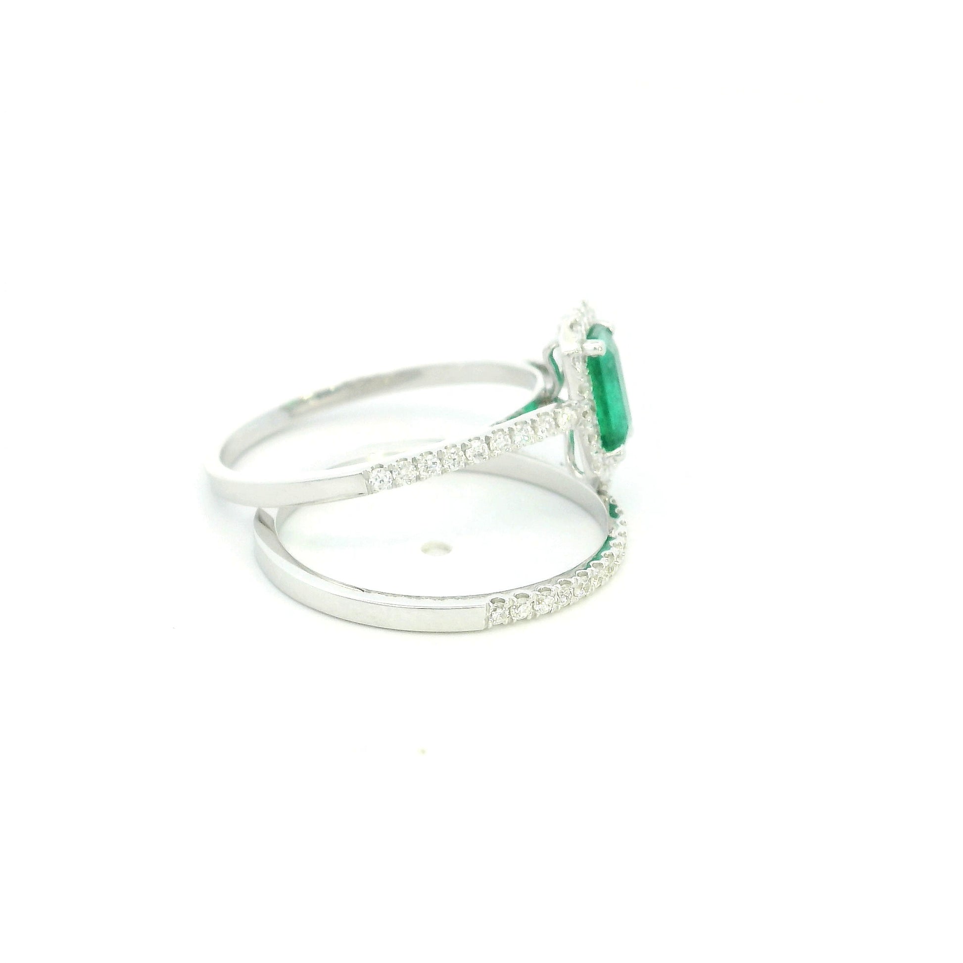 18K white gold emerald bridal set featuring a 0.71 carat natural emerald-cut emerald with a diamond halo and matching diamond wedding band.
