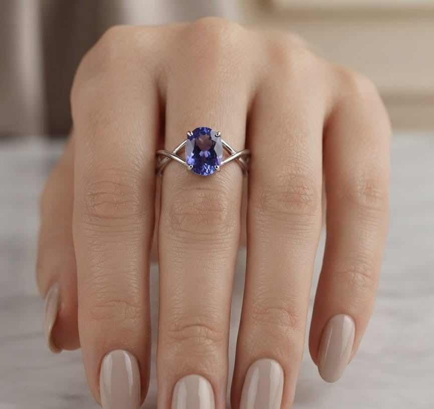 Oval tanzanite solitaire ring with sculptural crossover band in 18K white gold.