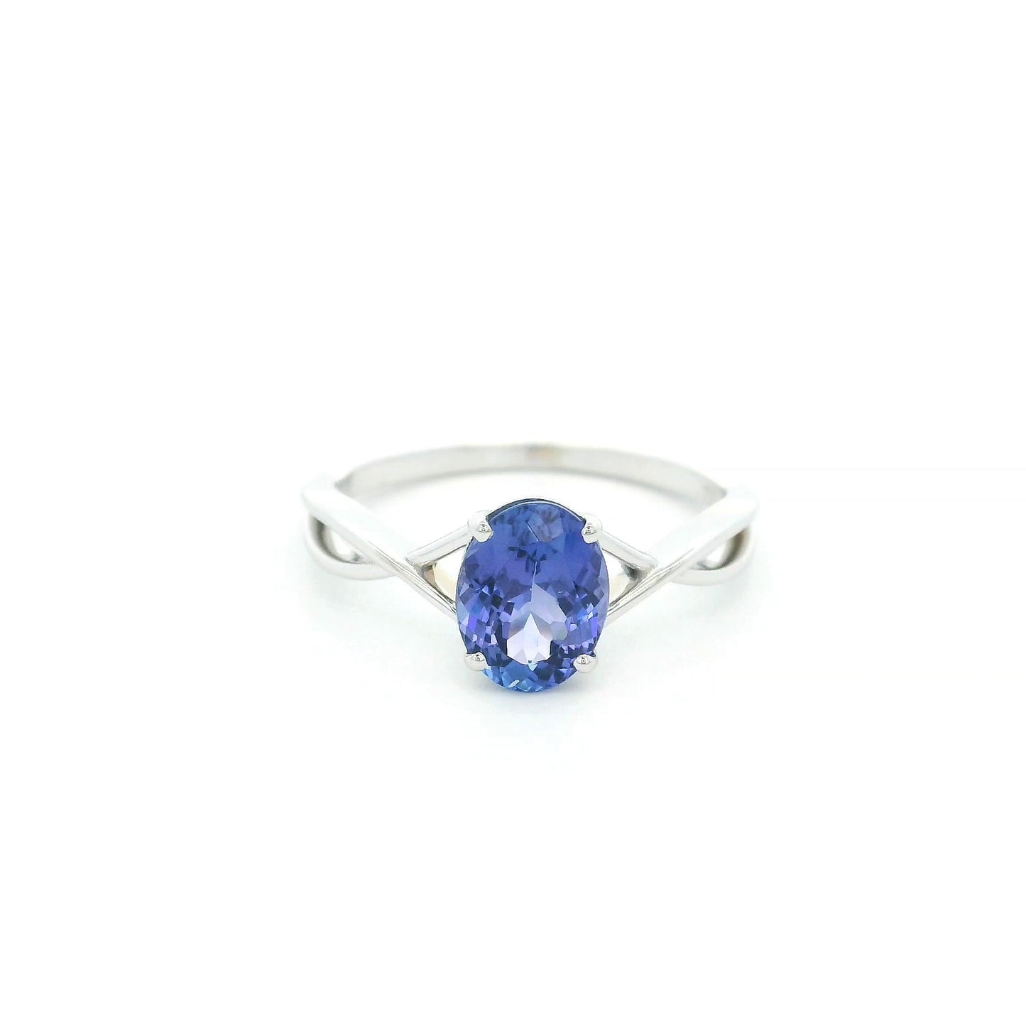 Oval tanzanite solitaire ring with sculptural crossover band in 18K white gold.