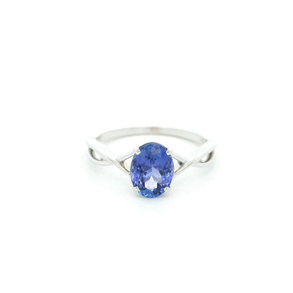 Oval tanzanite solitaire ring with sculptural crossover band in 18K white gold.