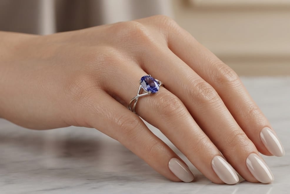 Oval tanzanite solitaire ring with sculptural crossover band in 18K white gold.