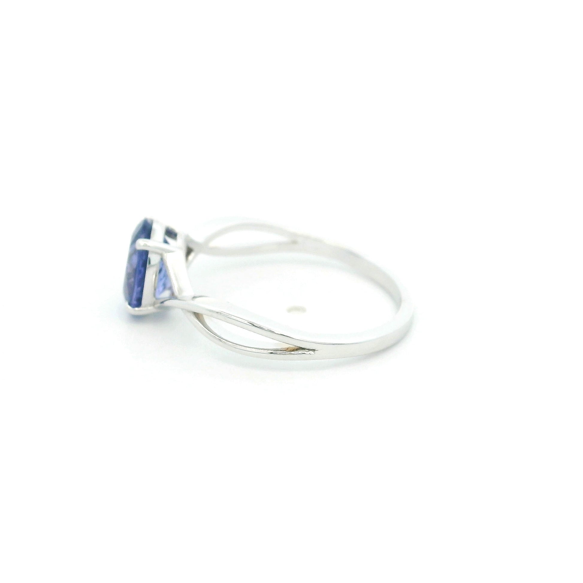 Oval tanzanite solitaire ring with sculptural crossover band in 18K white gold.