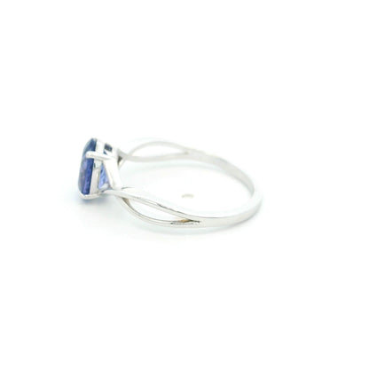 Oval tanzanite solitaire ring with sculptural crossover band in 18K white gold.