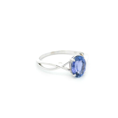 Oval tanzanite solitaire ring with sculptural crossover band in 18K white gold.