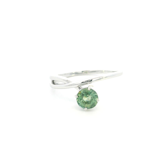 18K white gold crossover ring featuring a natural 0.88 carat round green sapphire in a contemporary solitaire design.