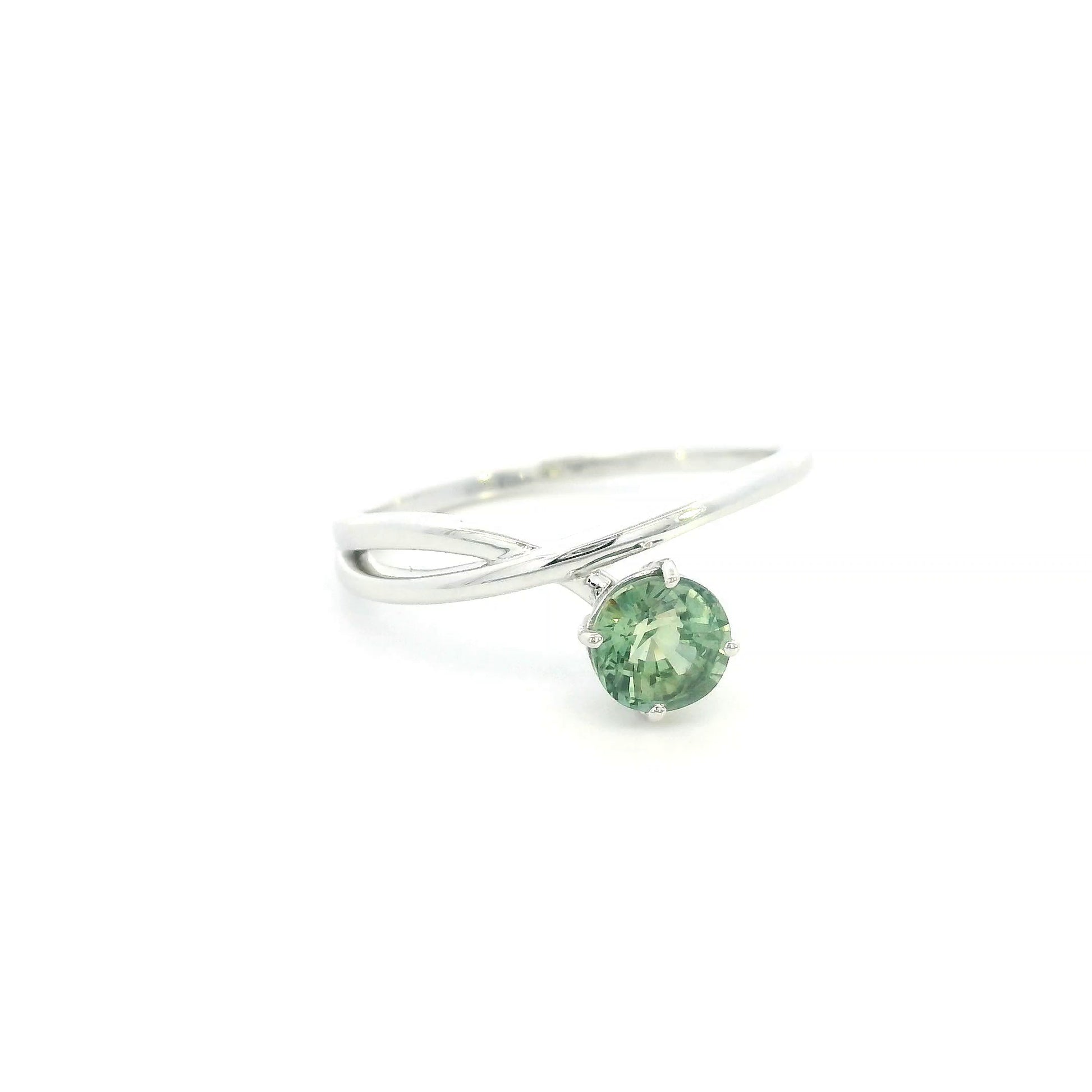 18K white gold crossover ring featuring a natural 0.88 carat round green sapphire in a contemporary solitaire design.