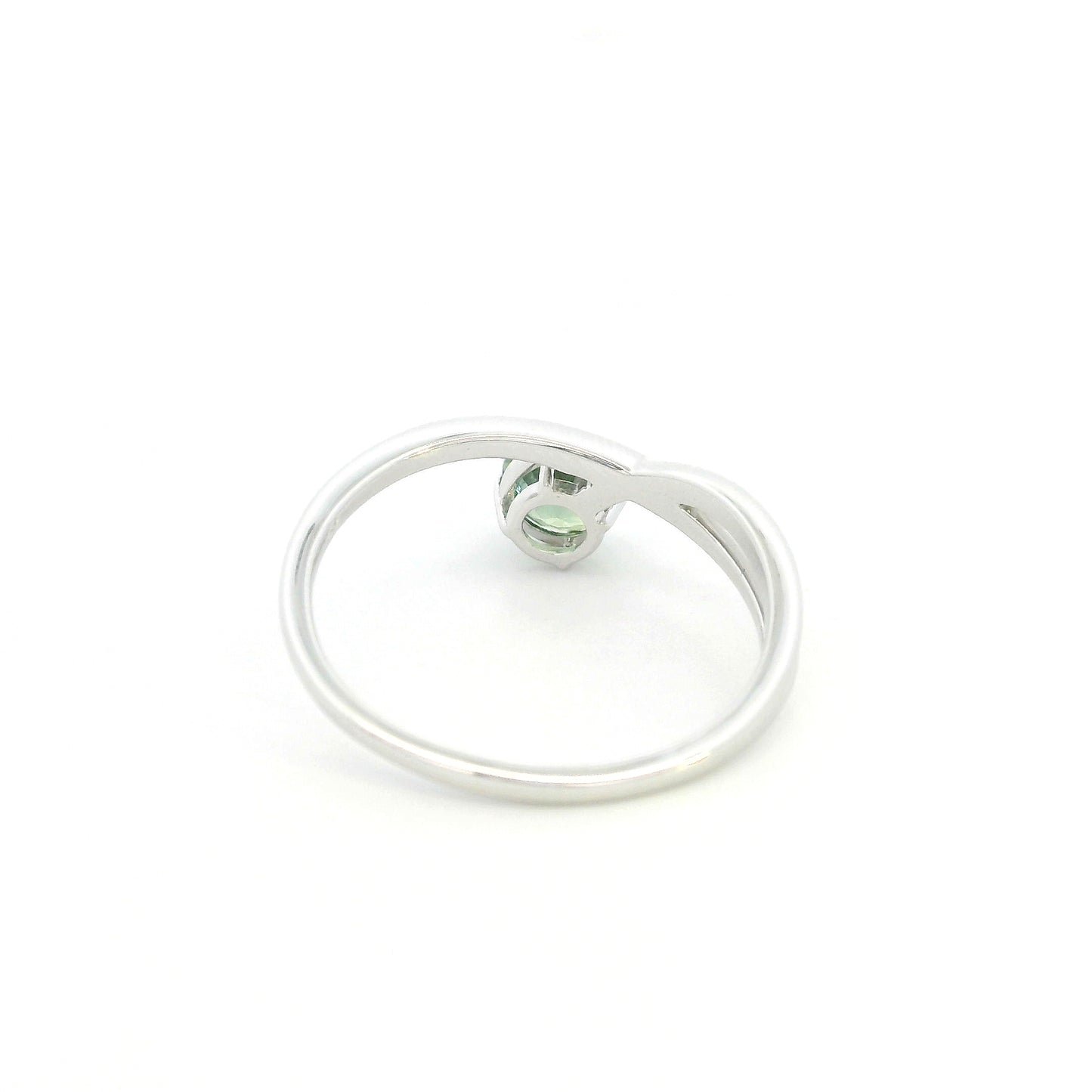 18K white gold crossover ring featuring a natural 0.88 carat round green sapphire in a contemporary solitaire design.