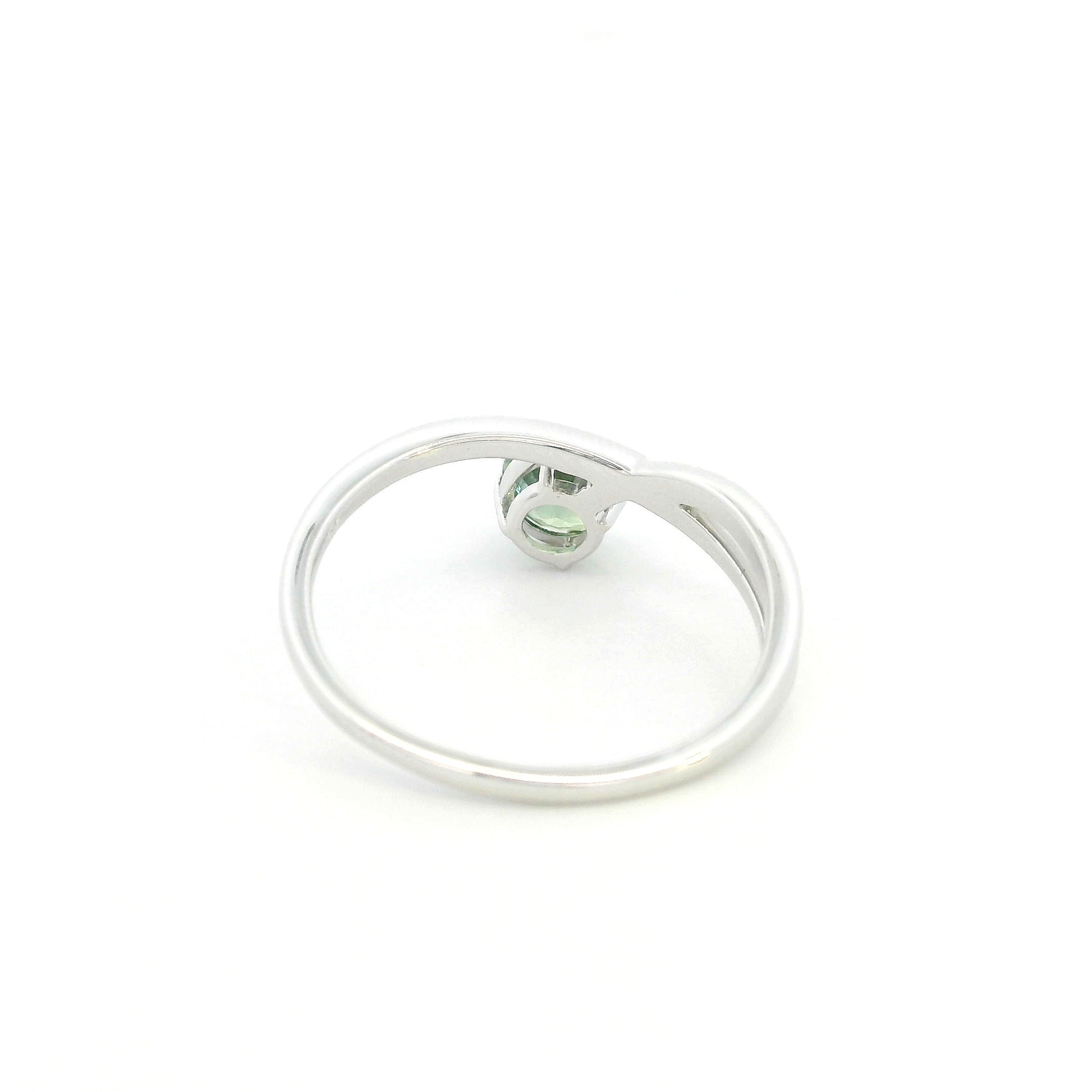 18K white gold crossover ring featuring a natural 0.88 carat round green sapphire in a contemporary solitaire design.