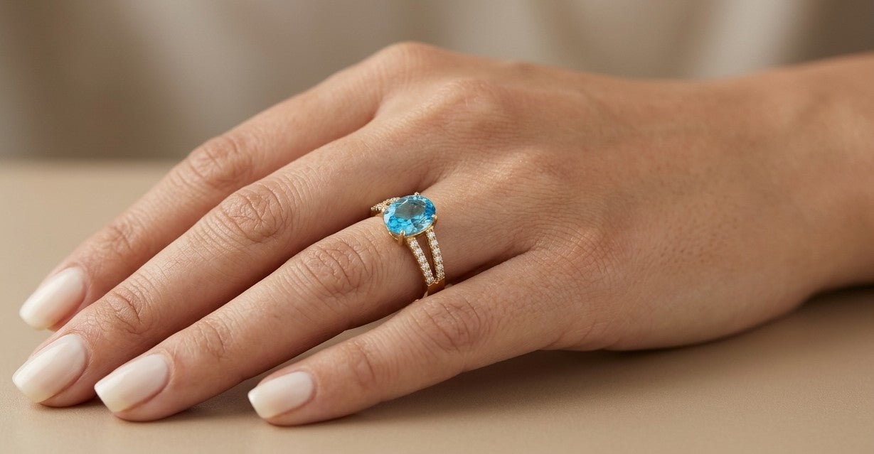 18K yellow gold Swiss blue topaz ring with oval centre stone and double-row diamond split shoulders.
