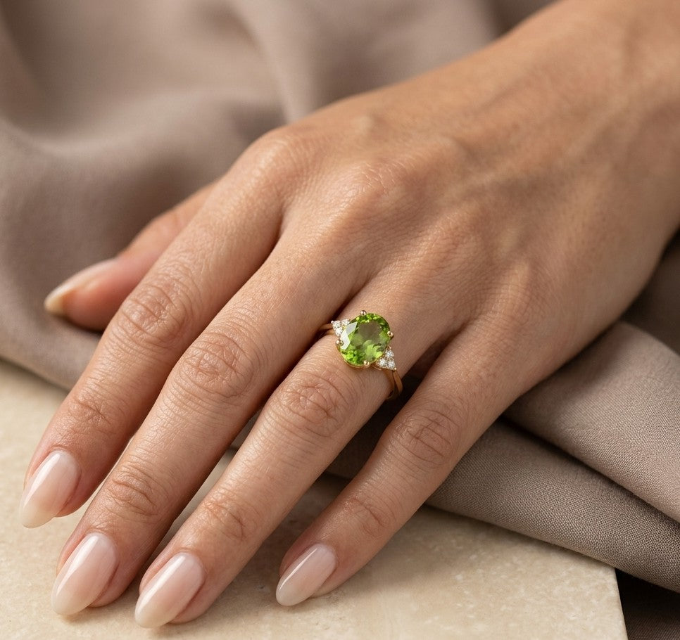 18K yellow gold peridot and diamond ring with oval green centre stone and diamond side accents.