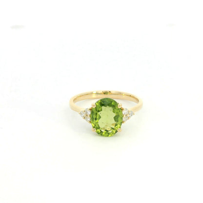 18K yellow gold peridot and diamond ring with oval green centre stone and diamond side accents.