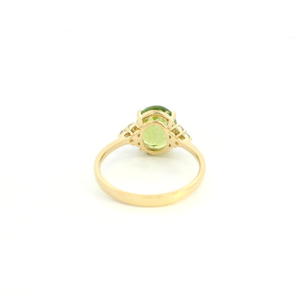 18K yellow gold peridot and diamond ring with oval green centre stone and diamond side accents.
