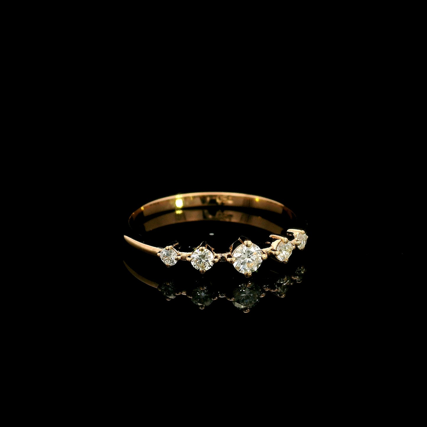 Diamond band ring in 18K rose gold with graduated round brilliant diamonds and larger centre diamond