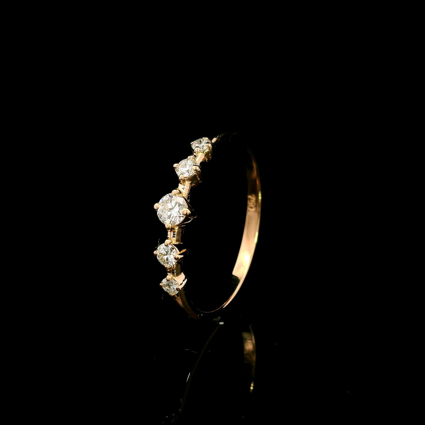 Diamond band ring in 18K rose gold with graduated round brilliant diamonds and larger centre diamond
