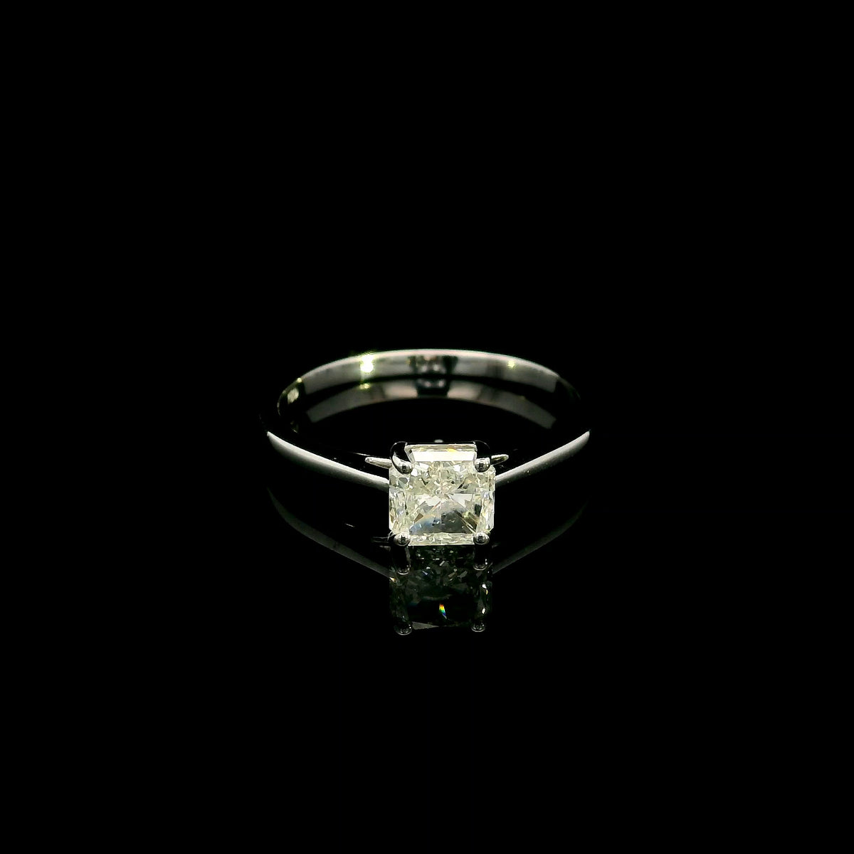Radiant cut diamond solitaire engagement ring in 18K white gold with a four-prong setting and polished band.
