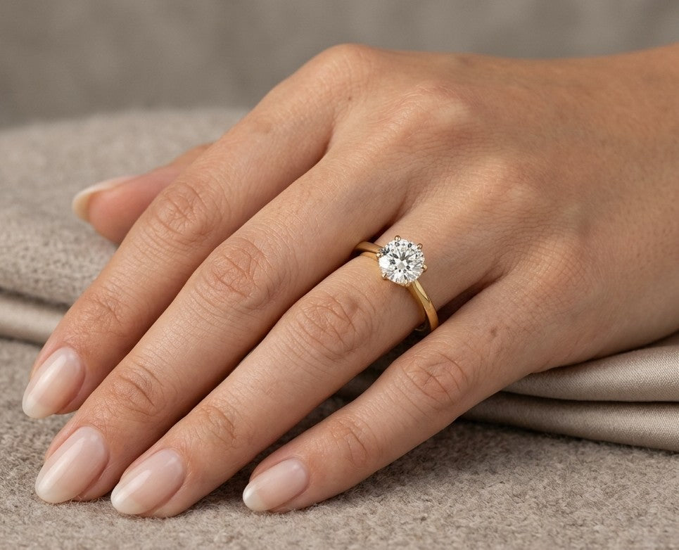 1 carat round diamond solitaire engagement ring in 18K yellow gold worn on hand