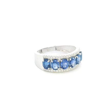 Blue sapphire and diamond band ring in 18K white gold featuring oval blue sapphires framed by rows of round brilliant diamonds.