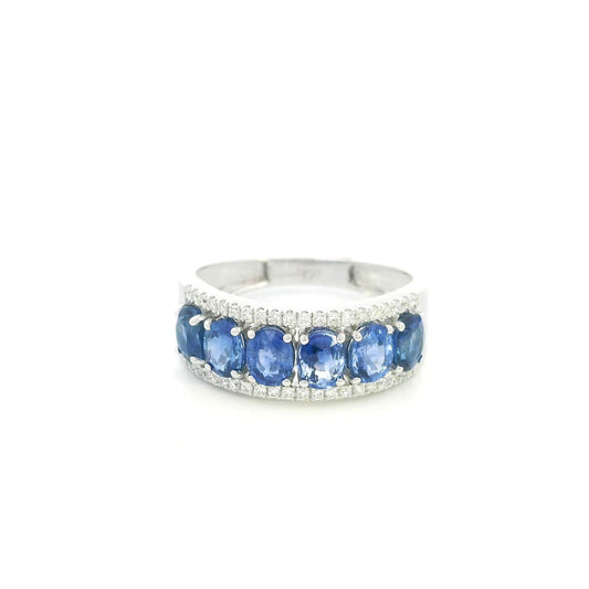 Blue sapphire and diamond band ring in 18K white gold featuring oval blue sapphires framed by rows of round brilliant diamonds.