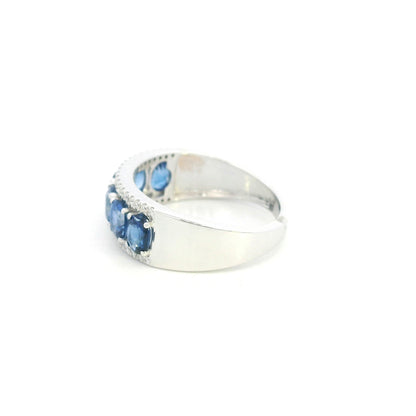 Blue sapphire and diamond band ring in 18K white gold featuring oval blue sapphires framed by rows of round brilliant diamonds.