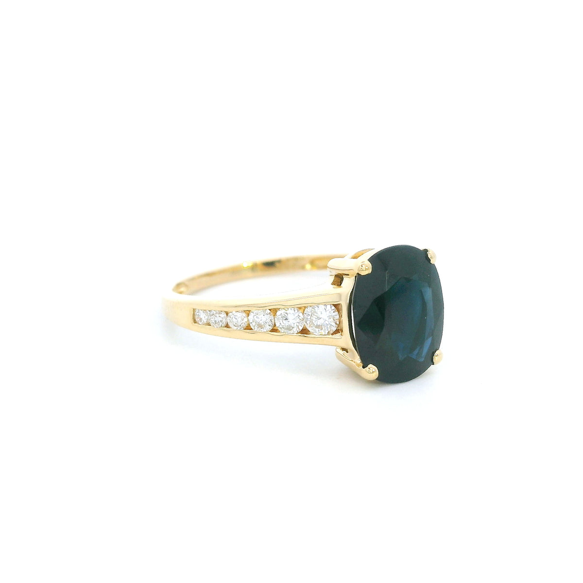 Blue sapphire and diamond ring in 18K yellow gold featuring an oval blue sapphire with round brilliant diamond-set shoulders.