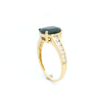 Blue sapphire and diamond ring in 18K yellow gold featuring an oval blue sapphire with round brilliant diamond-set shoulders.