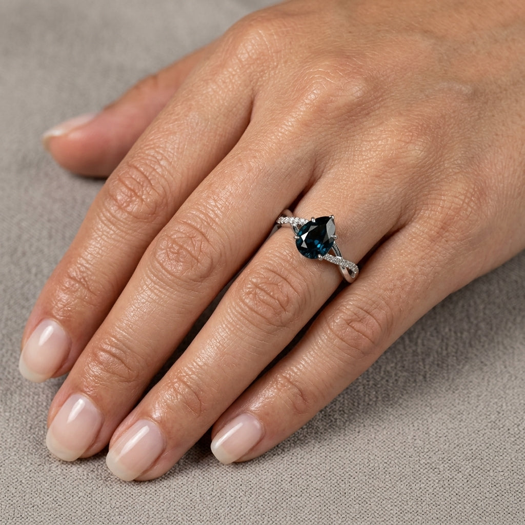 Pear shaped blue sapphire and diamond twist ring in 18K white gold