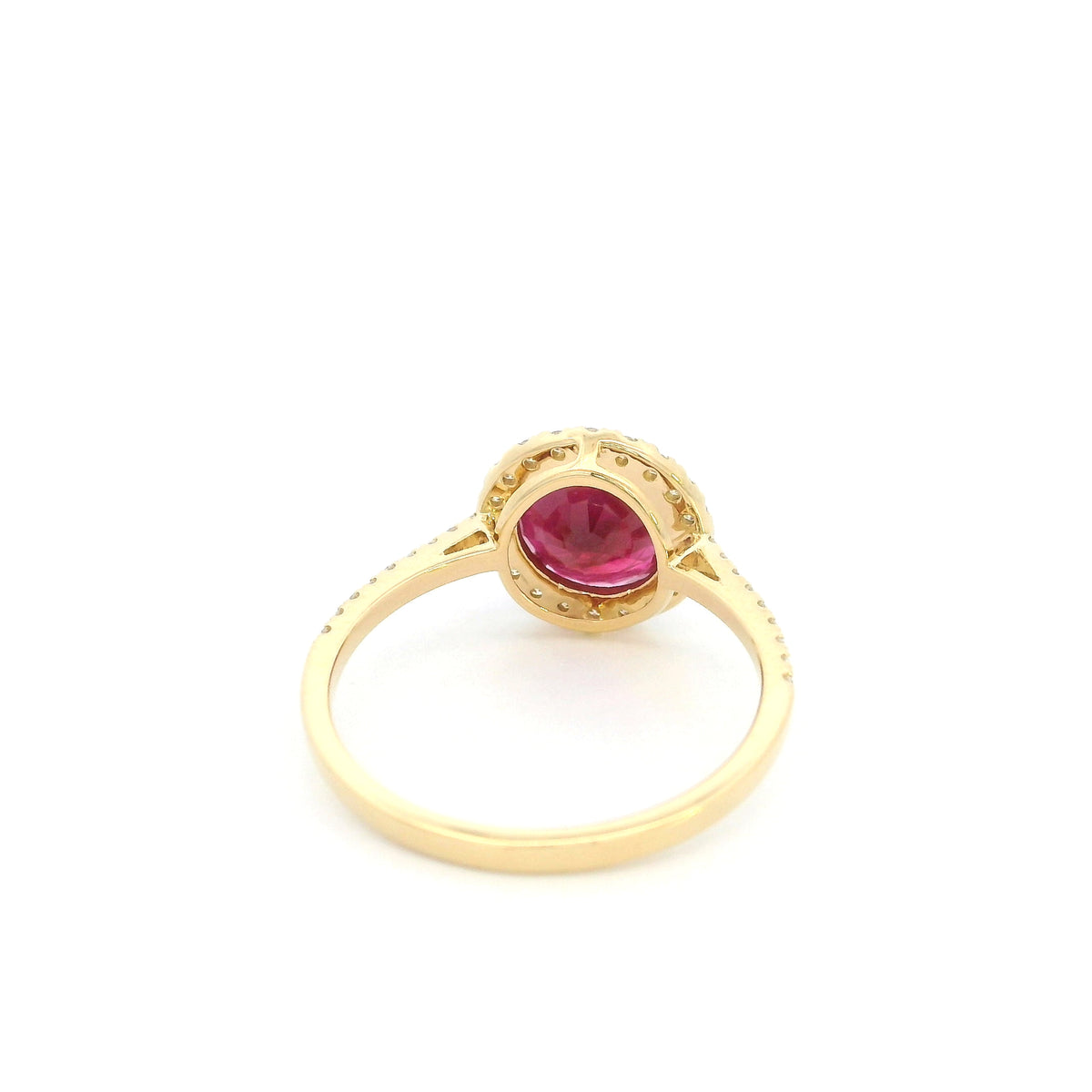Ruby and diamond halo ring in 18K yellow gold featuring a round red ruby surrounded by diamonds with diamond-set shoulders.