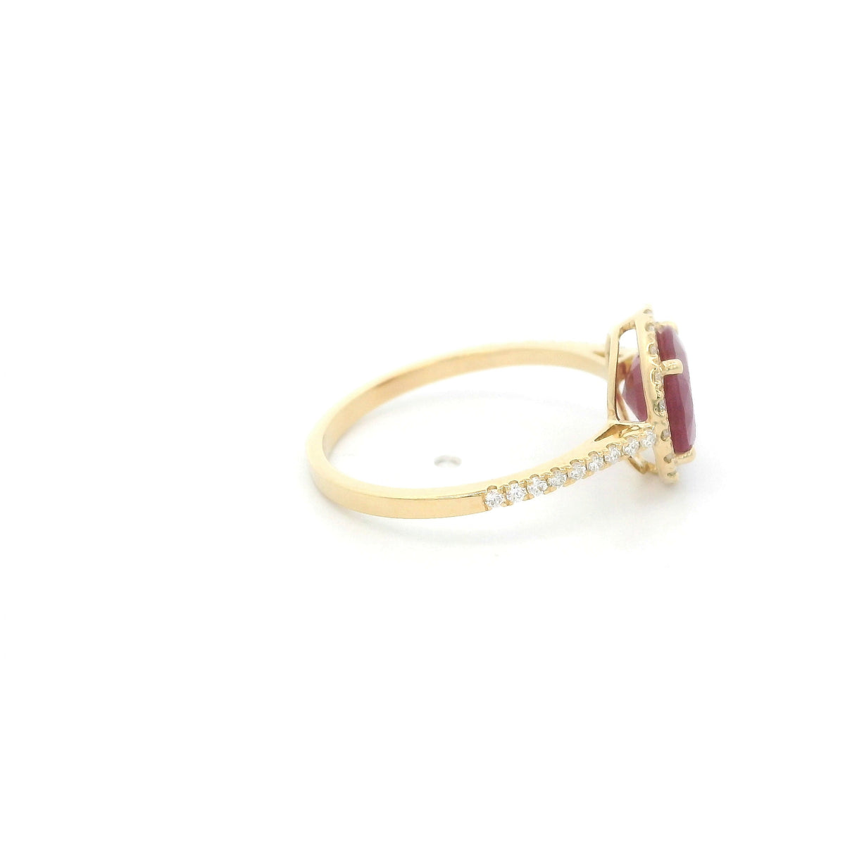 Ruby and diamond halo ring in 18K yellow gold featuring a round red ruby surrounded by diamonds with diamond-set shoulders.