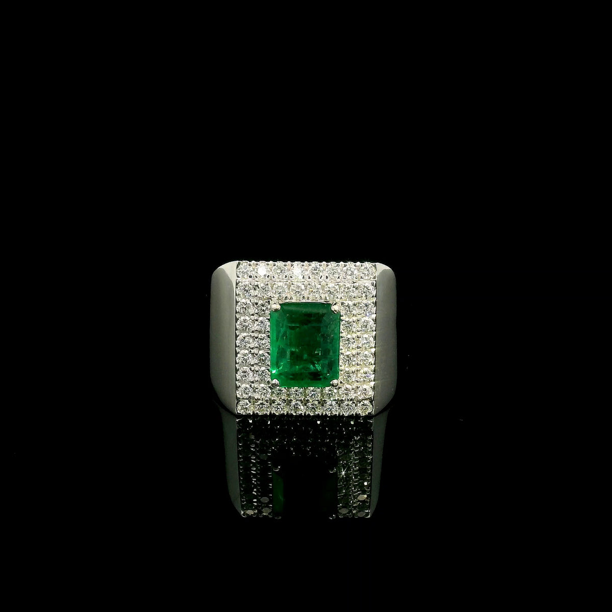 Men’s emerald and diamond statement ring in 18K white gold with rectangular green emerald and diamond surround.