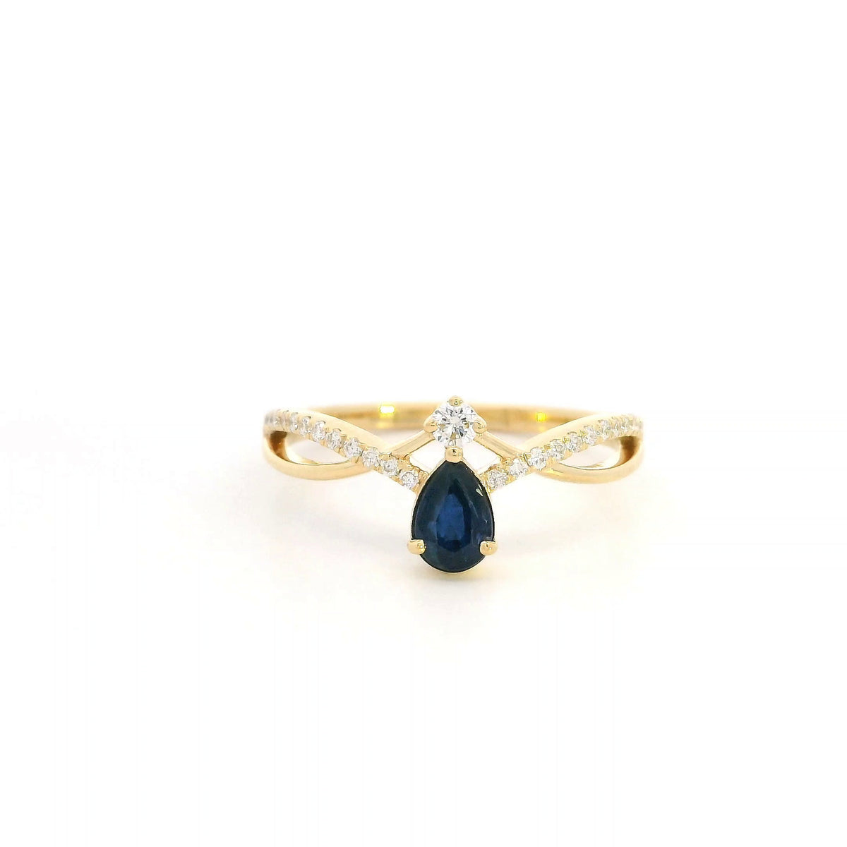 Pear shaped blue sapphire and diamond ring in 18K yellow gold with sweeping diamond-set design.