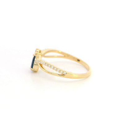 Pear shaped blue sapphire and diamond ring in 18K yellow gold with sweeping diamond-set design.