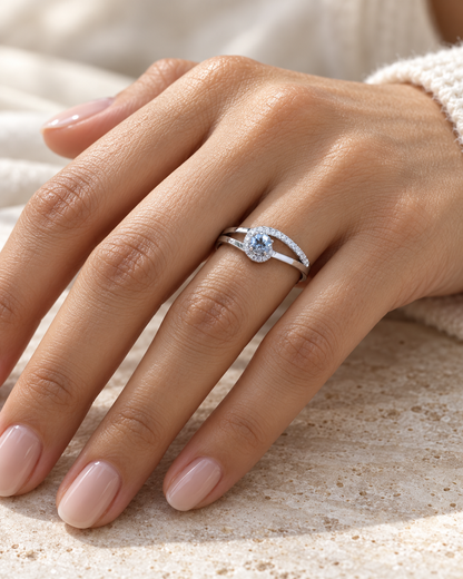 18K white gold ring with a round cut aquamarine, a curved row of diamonds wrapping around the gemstone and a polished gold band.