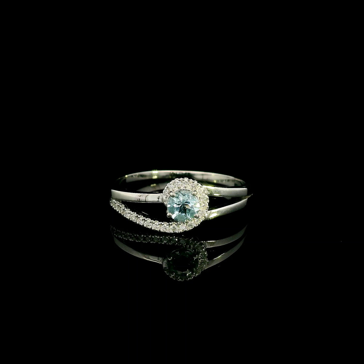 18K white gold ring with a round cut aquamarine, a curved row of diamonds wrapping around the gemstone and a polished gold band.