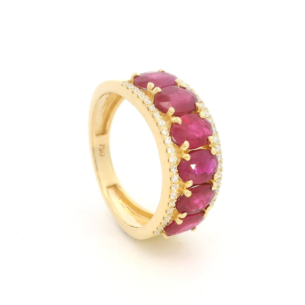 Oval ruby and diamond band ring in 18K yellow gold with a row of rubies framed by round diamonds.