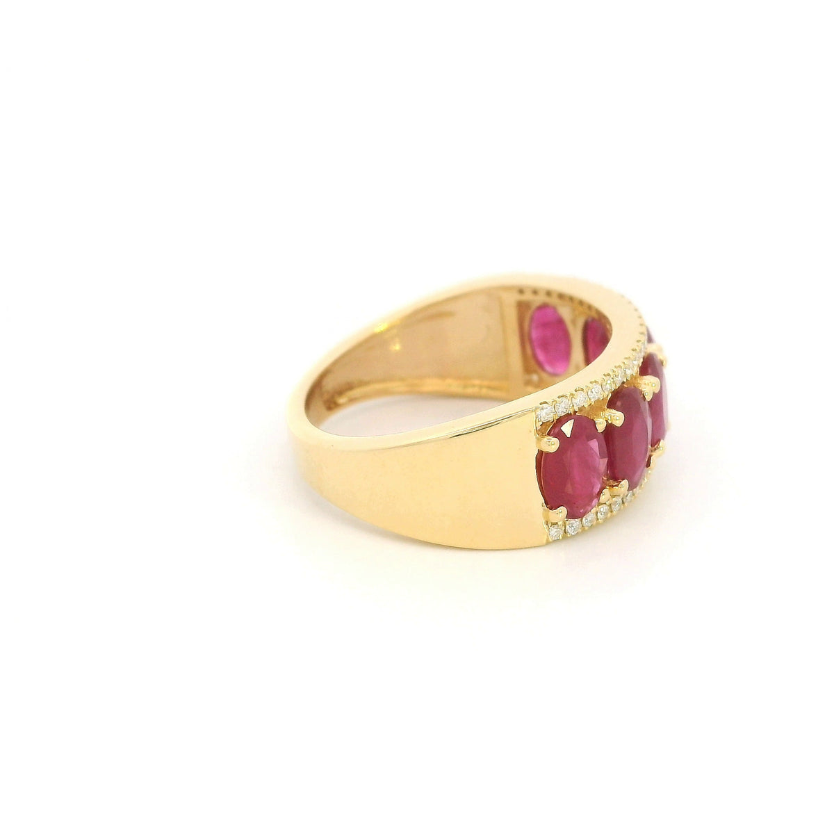 Oval ruby and diamond band ring in 18K yellow gold with a row of rubies framed by round diamonds.