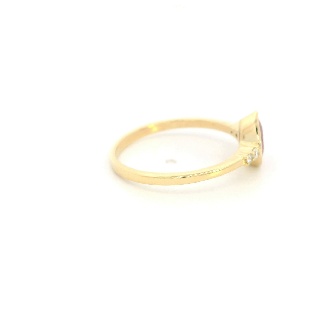 Pear-shaped red ruby ring in 18K yellow gold with a smooth bezel setting and small round diamonds along both shoulders.