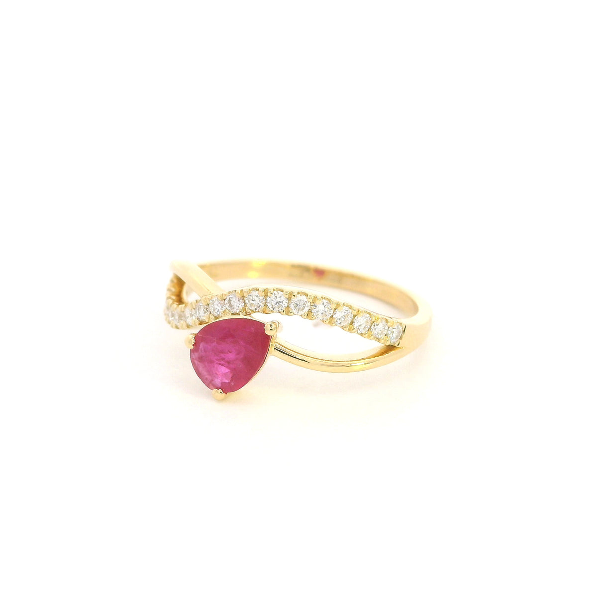 Pear shaped ruby and diamond ring in 18K yellow gold featuring a sweeping diamond-set curved band and asymmetrical design.