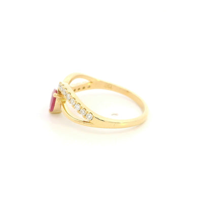 Pear shaped ruby and diamond ring in 18K yellow gold featuring a sweeping diamond-set curved band and asymmetrical design.