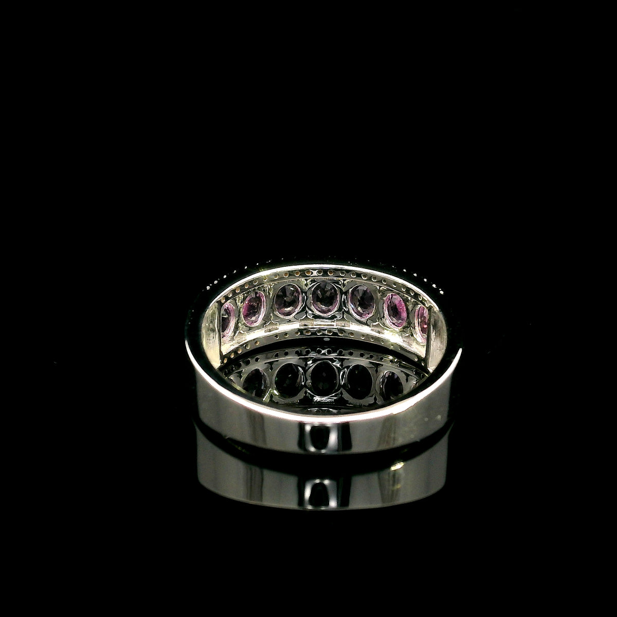 Pink sapphire and diamond band ring in 18K white gold featuring oval pink sapphires framed by two rows of sparkling diamonds.