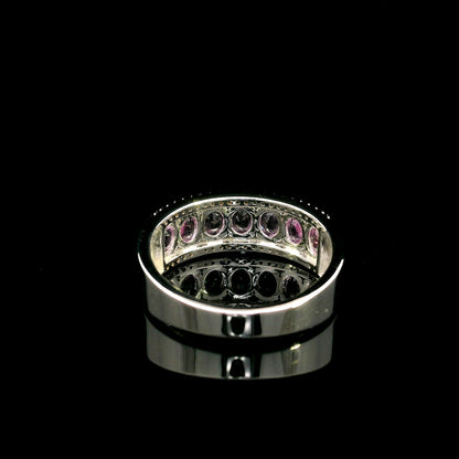 Pink sapphire and diamond band ring in 18K white gold featuring oval pink sapphires framed by two rows of sparkling diamonds.