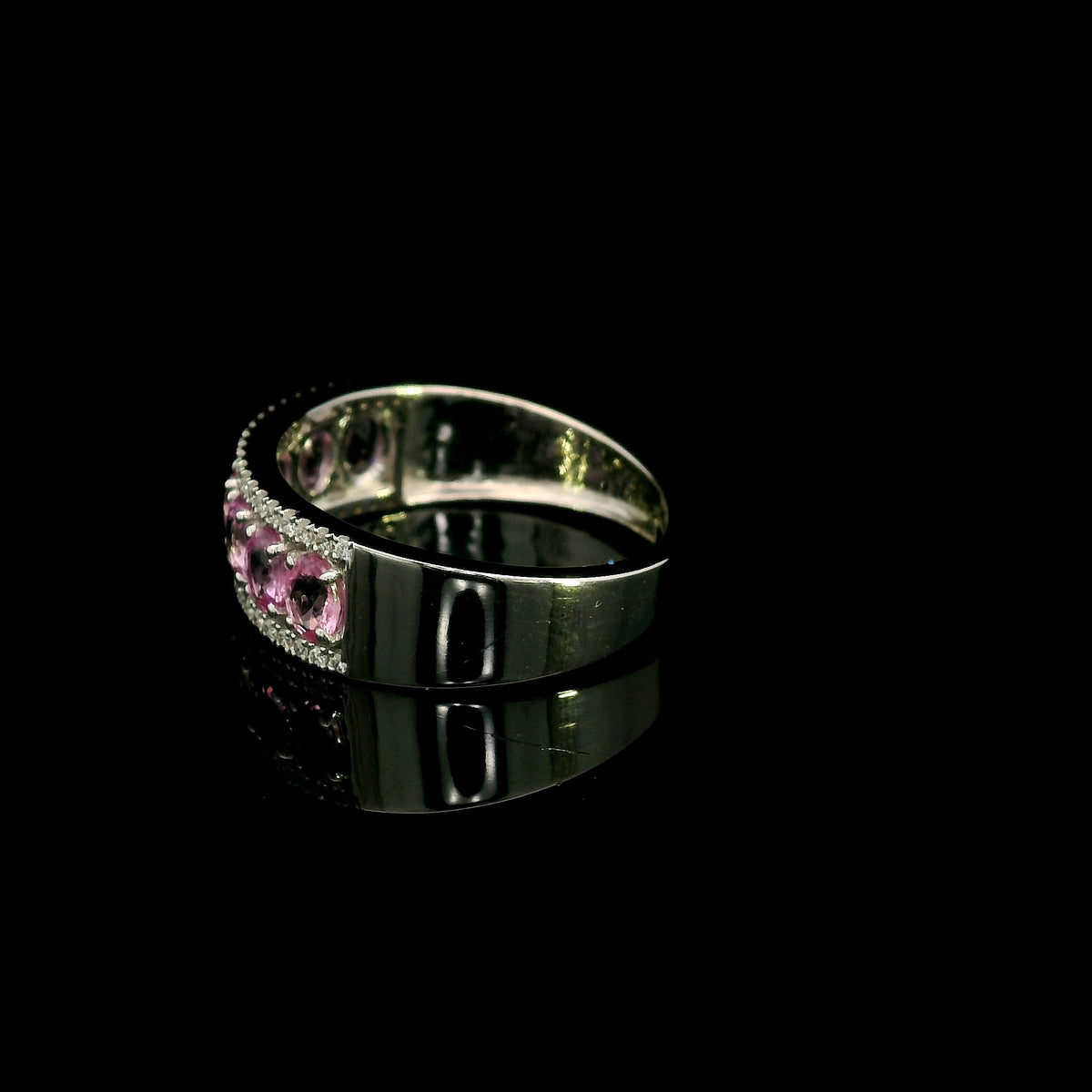 Pink sapphire and diamond band ring in 18K white gold featuring oval pink sapphires framed by two rows of sparkling diamonds.