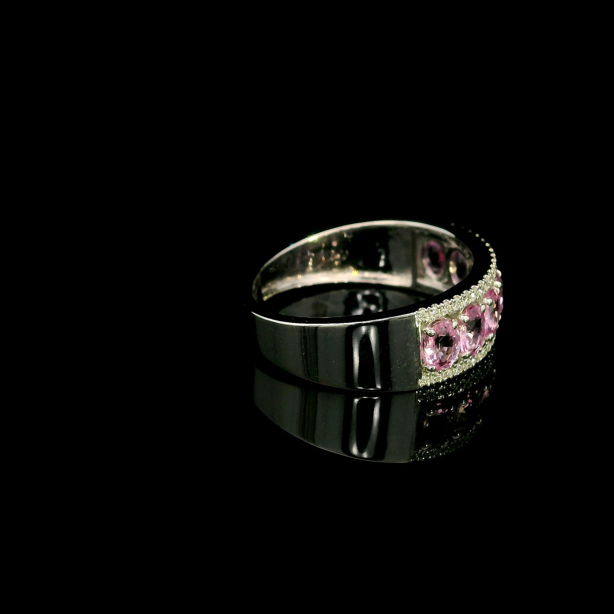 Pink sapphire and diamond band ring in 18K white gold featuring oval pink sapphires framed by two rows of sparkling diamonds.
