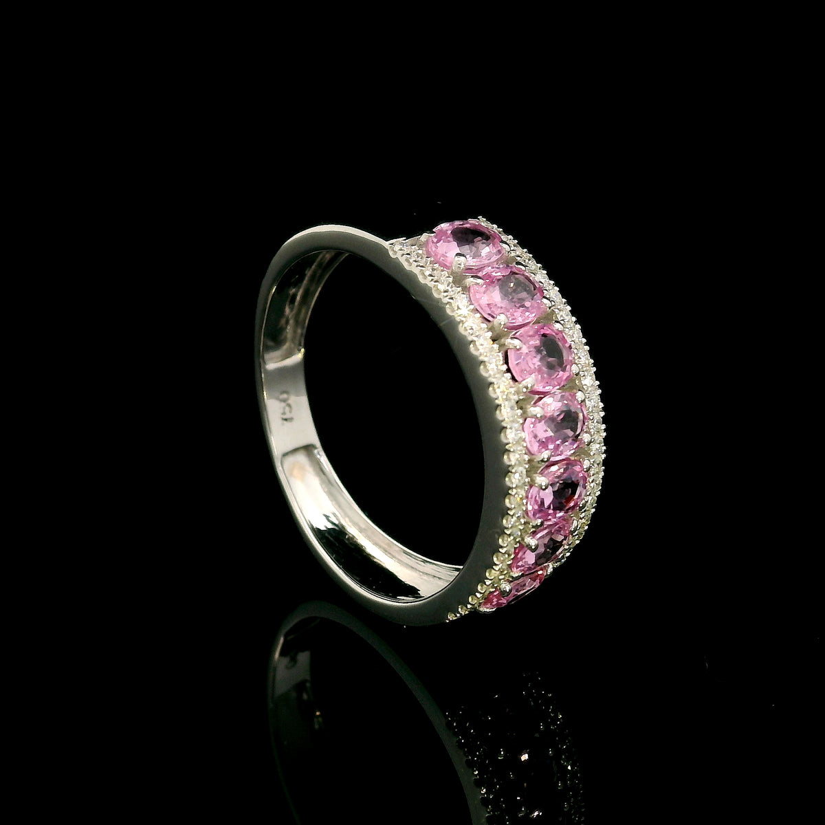 Pink sapphire and diamond band ring in 18K white gold featuring oval pink sapphires framed by two rows of sparkling diamonds.