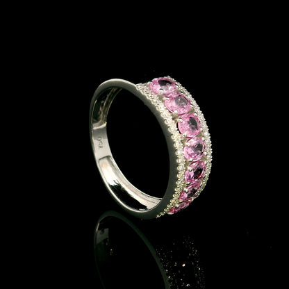 Pink sapphire and diamond band ring in 18K white gold featuring oval pink sapphires framed by two rows of sparkling diamonds.