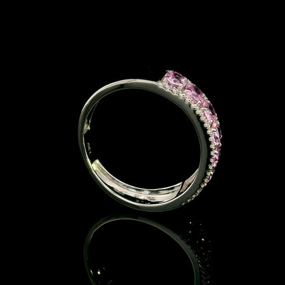 Pink sapphire and diamond band ring in 18K white gold featuring oval pink sapphires framed by two rows of sparkling diamonds.