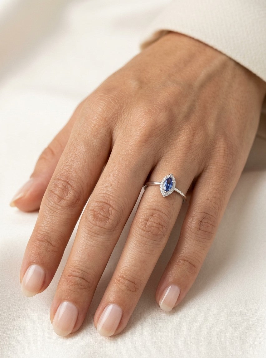 Dainty marquise tanzanite and diamond halo ring in 18K white gold with a slim polished band.