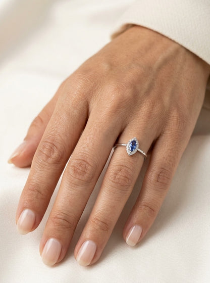 Dainty marquise tanzanite and diamond halo ring in 18K white gold with a slim polished band.