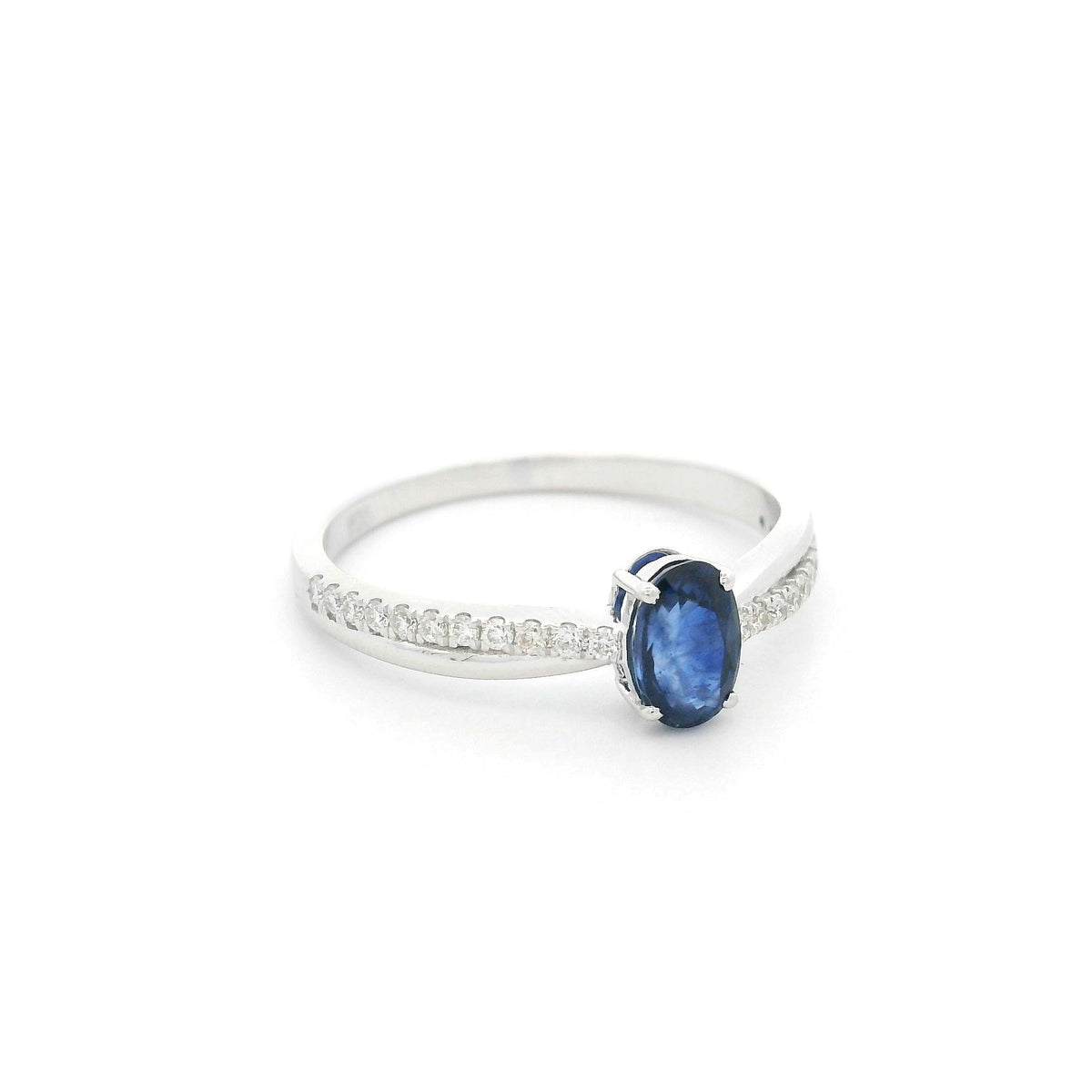 Oval blue sapphire ring with diamond-set shoulders in polished 18K white gold, featuring a four-prong centre gemstone setting.