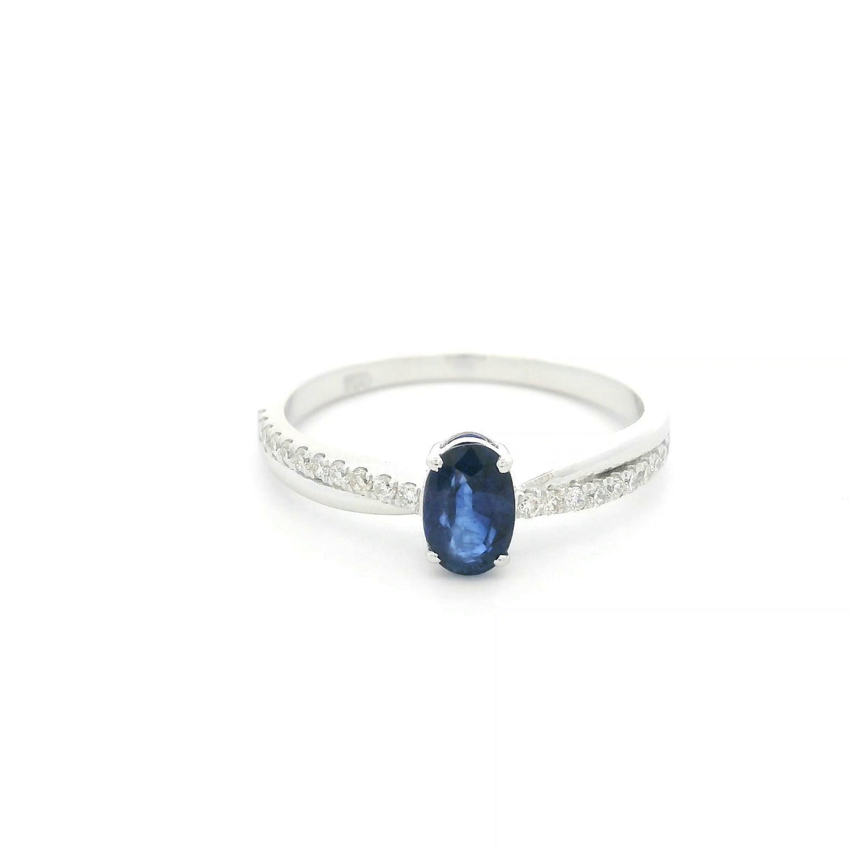 Oval blue sapphire ring with diamond-set shoulders in polished 18K white gold, featuring a four-prong centre gemstone setting.